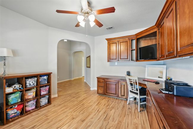 Office area with ceiling fan, arched walkways, light wood-style floors, and built in desk | Image 12