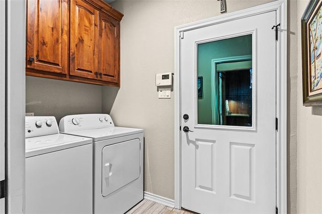 Clothes washing area featuring light wood-type flooring, cabinets, and washer and clothes dryer | Image 23