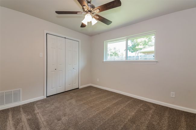Unfurnished bedroom featuring dark colored carpet, a closet, and a ceiling fan | Image 21