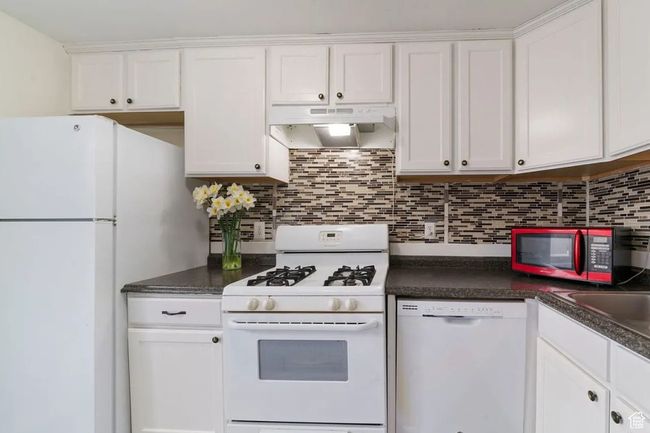 Kitchen featuring white cabinetry, under cabinet range hood, and white appliances | Image 10
