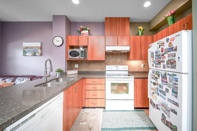 Kitchen with a sink, dark stone counters, decorative backsplash, white appliances, and under cabinet range hood | Image 18