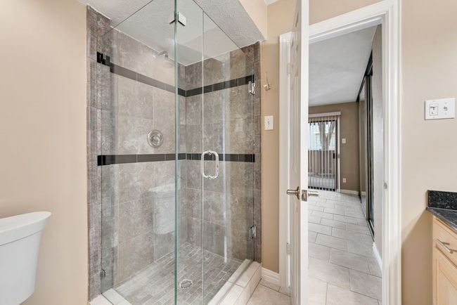 Bathroom featuring vanity, tile patterned flooring, toilet, a stall shower, and baseboards | Image 8