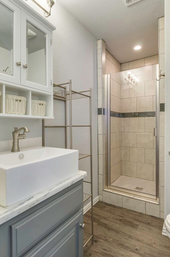 Full bathroom featuring a shower stall, vanity, wood finished floors, and a textured ceiling | Image 25