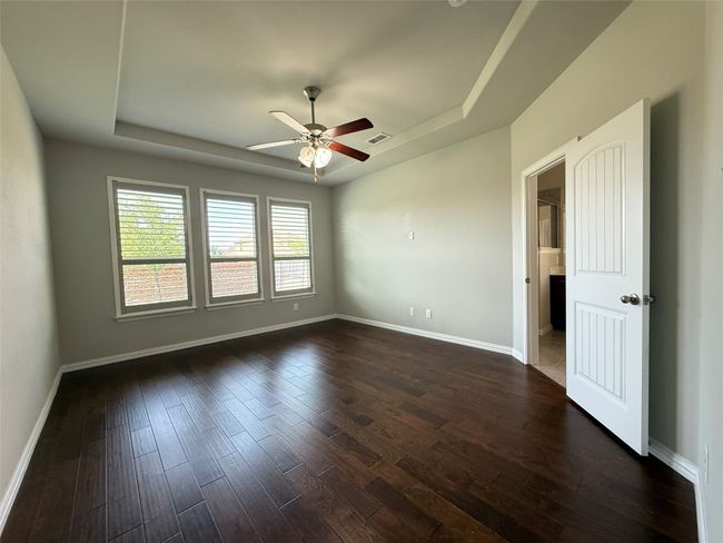 Spare room with a tray ceiling, ceiling fan, dark wood-style floors, and baseboards | Image 8