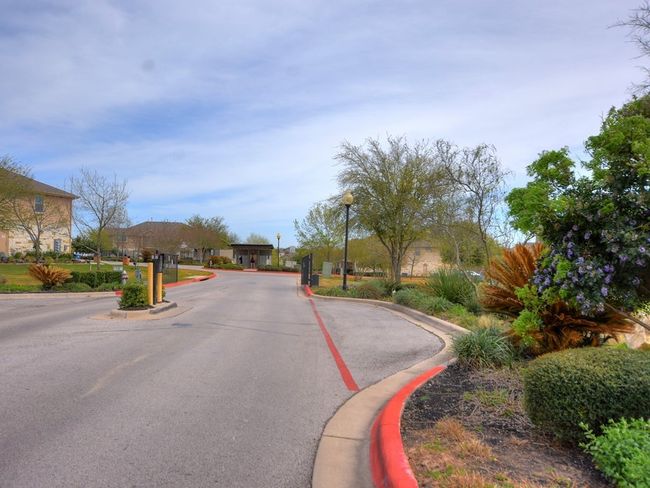 View of street featuring a gated entry, curbs, and street lights | Image 27