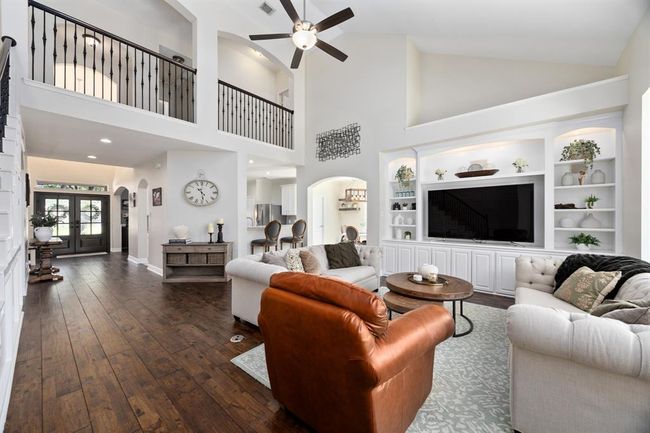 The open floorplan features soaring ceilings, custom built-ins, and a stunning custom millwork wall along the staircase. | Image 8