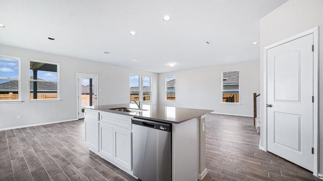 Kitchen featuring stainless steel dishwasher, dark wood-type flooring, a kitchen island with sink, white cabinetry, and recessed lighting | Image 12