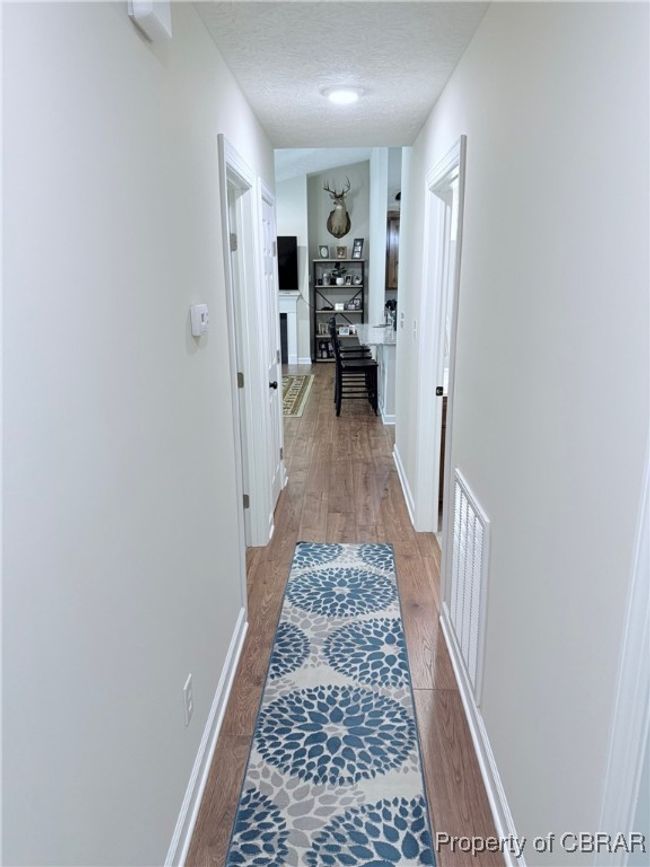 Hall to all bedrooms and bathrooms with --Waterproof Pergo llight wood-style floors, a textured ceiling, and baseboards | Image 10