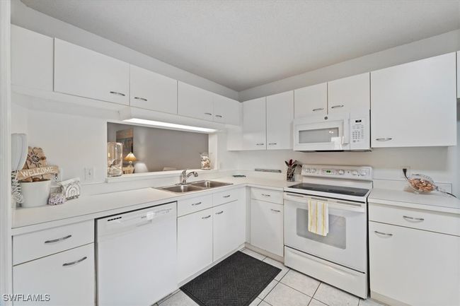 Kitchen featuring white cabinets, a sink, light countertops, white appliances, and light tile patterned flooring | Image 6