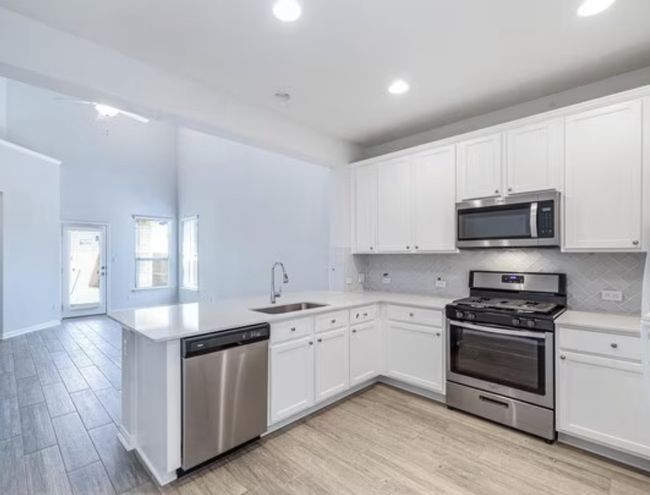 Kitchen with stainless steel appliances, a peninsula, light countertops, backsplash, and recessed lighting | Image 4