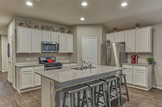 Beautiful island kitchen with gleaming granite countertops, 4-burner gas range, tile backsplash, walk-in pantry and a water filtration system on the sink. | Image 22