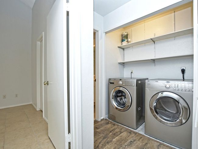 Clothes washing area with light tile patterned floors, independent washer and dryer, laundry area, and baseboards | Image 8