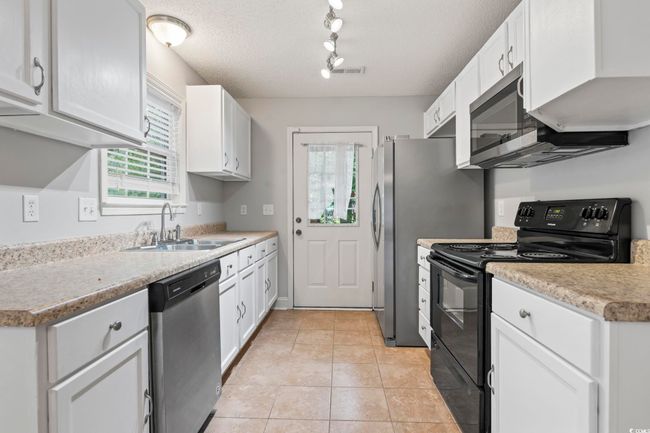 Kitchen with appliances with stainless steel finishes, a sink, rail lighting, healthy amount of natural light, and a textured ceiling | Image 11