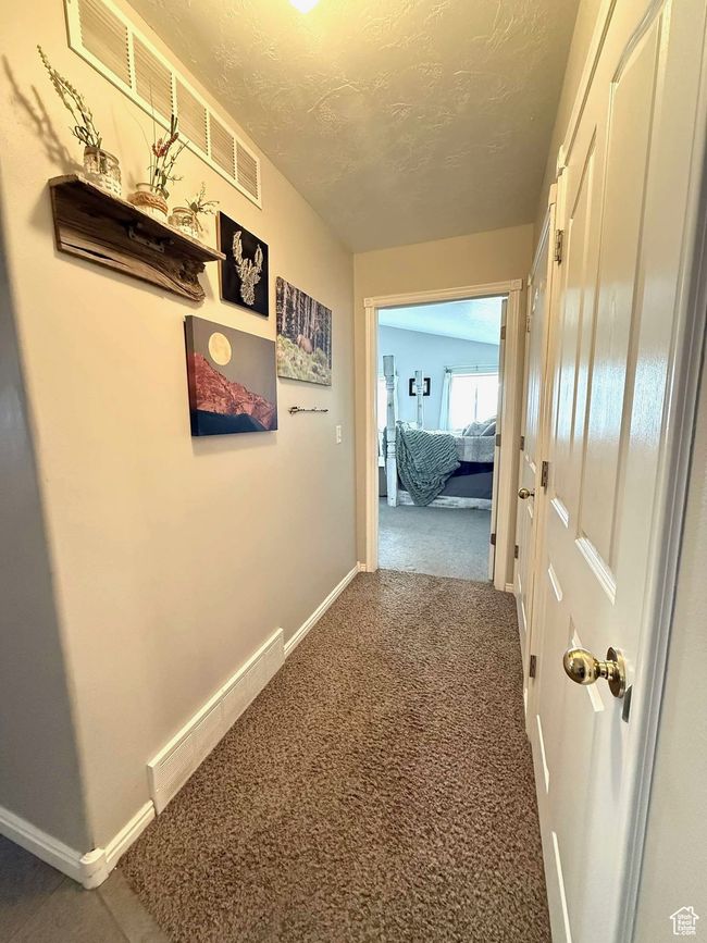 Corridor featuring a textured ceiling, baseboards, and carpet floors | Image 53