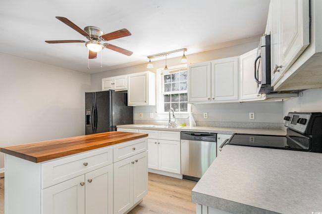 Kitchen with butcher block counters, appliances with stainless steel finishes, a sink, white cabinetry, and a ceiling fan | Image 8