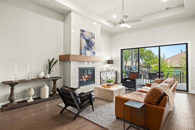 Living area with wood finished floors, recessed lighting, ceiling fan, a fireplace, and a high ceiling | Image 12
