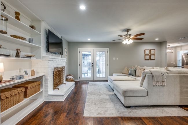 Living room with wood finished floors, recessed lighting, ceiling fan, a fireplace, and french doors | Image 14