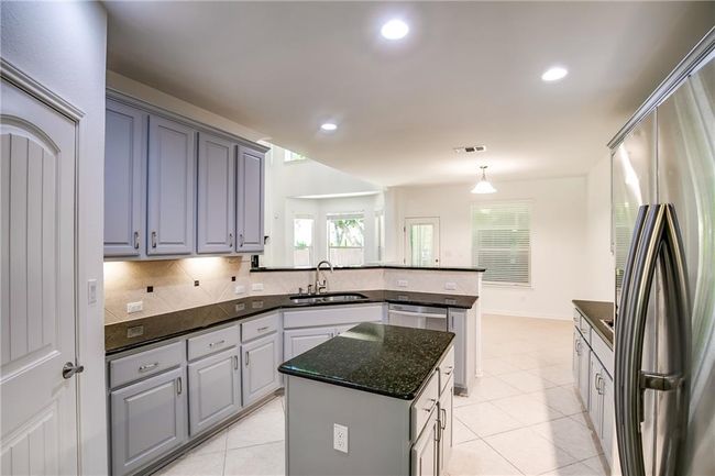 Kitchen featuring stainless steel appliances, a peninsula, tasteful backsplash, a center island, and light tile patterned floors | Image 13