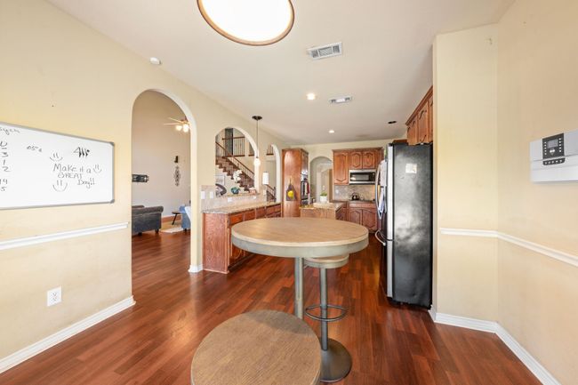 Kitchen featuring dark wood-style floors, light countertops, brown cabinets, stainless steel appliances, and arched walkways | Image 7