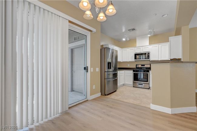 Kitchen featuring a notable chandelier, stainless steel appliances, visible vents, white cabinets | Image 8