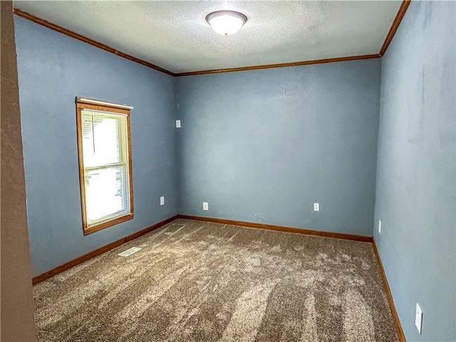 Carpeted spare room featuring visible vents, crown molding, a textured ceiling, and baseboards | Image 15