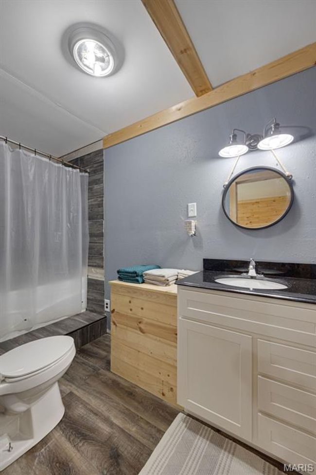 Full bath with wood finished floors, toilet, vanity, and shower / tub combo with curtain | Image 12