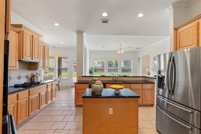 The chef-inspired kitchen includes granite countertops, a gas cooktop, an island, and plenty of cabinetry. | Image 8