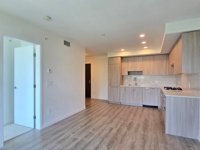 Kitchen featuring light brown cabinets, modern cabinets, light countertops, light wood finished floors, and tasteful backsplash | Image 6