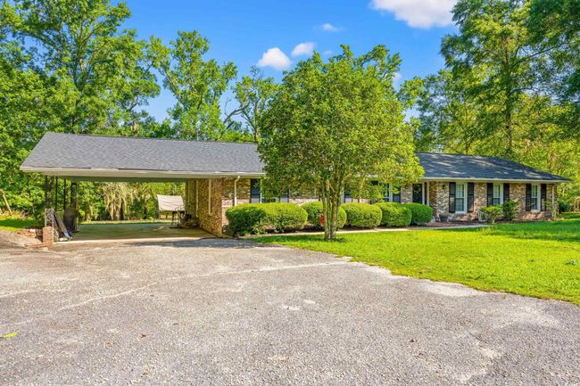 Ranch-style home featuring driveway, a front lawn, a carport, brick siding, and roof with shingles | Image 20