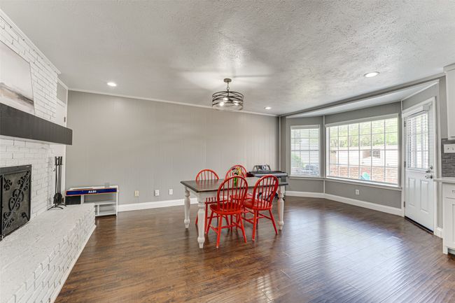 Dining space with a textured ceiling, a fireplace, dark wood finished floors, and recessed lighting | Image 8