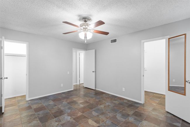 Unfurnished bedroom featuring visible vents, a walk in closet, stone finish floor, and a closet | Image 24