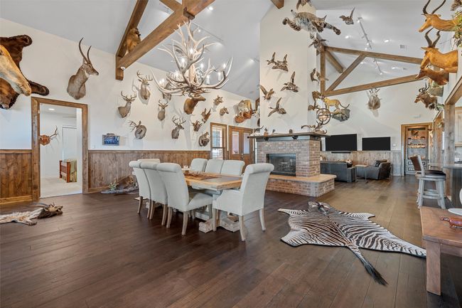 Dining room featuring a wainscoted wall, high vaulted ceiling, beamed ceiling, wood-type flooring, and a chandelier | Image 5