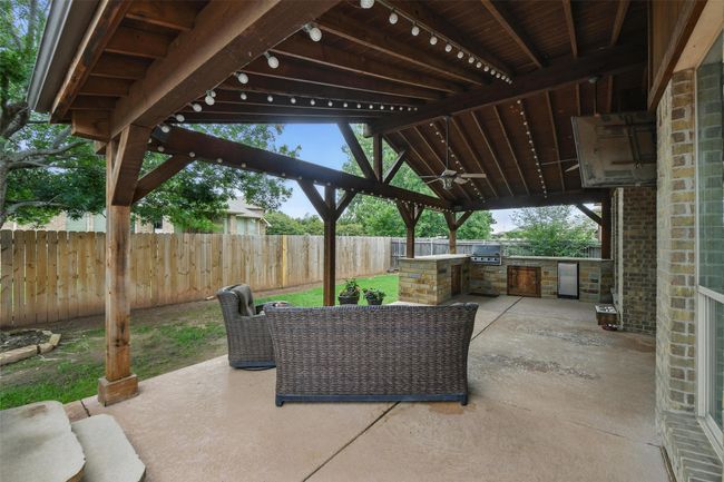 Fenced backyard featuring an outdoor kitchen, a gazebo, a ceiling fan, and a patio area | Image 7