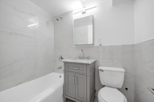 Bathroom featuring vanity, bathing tub / shower combination, and tile walls | Image 17