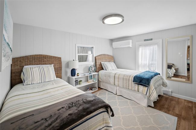 Bedroom featuring a baseboard radiator, wood finished floors, and a wall unit AC | Image 9