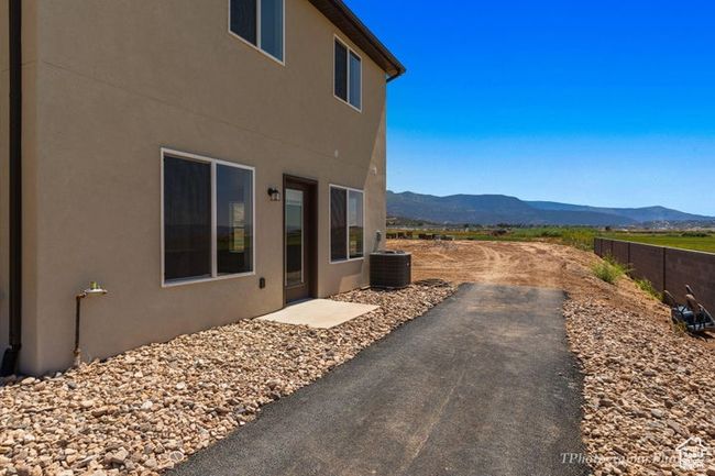 View of property exterior with a mountain view, stucco siding, central air condition unit, and a patio area | Image 19