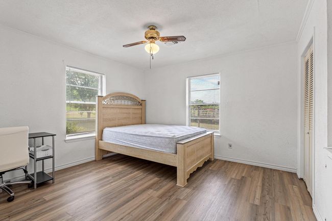 Bedroom featuring multiple windows, wood finished floors, crown molding, ceiling fan, and a textured ceiling | Image 27