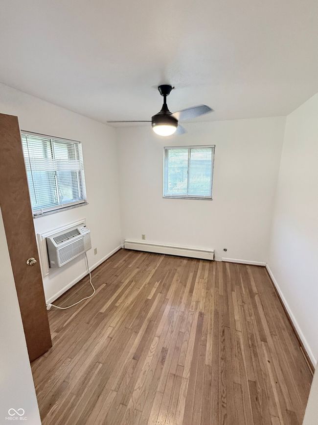 empty room with plenty of natural light, hardwood / wood-style floors, an AC wall unit, and a baseboard radiator | Image 10
