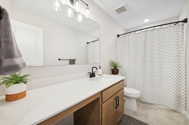 Bright and stylish full bath featuring a sleek white granite countertop with a single sink, ample space to sit and get ready, and a modern tub-shower combo for everyday comfort. | Image 33