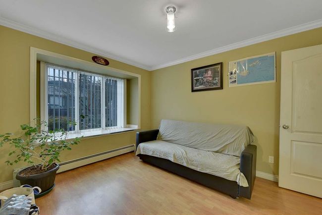 Living area with baseboard heating, wood finished floors, ornamental molding, and baseboards | Image 16
