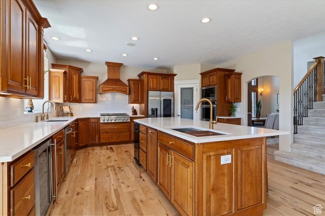 Kitchen featuring a sink, appliances with stainless steel finishes, custom range hood, and beverage cooler | Image 14
