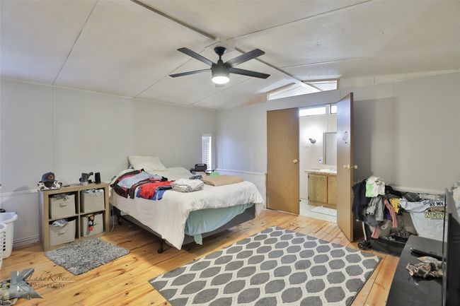 Bedroom featuring lofted ceiling with beams, connected bathroom, hardwood / wood-style floors, and a ceiling fan | Image 30