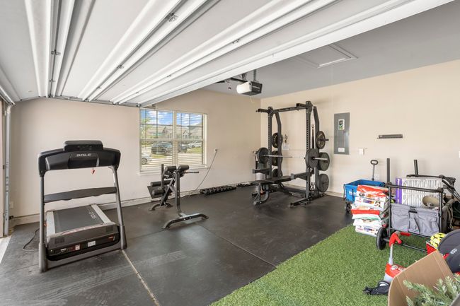 Workout area featuring electric panel, attic access, and a garage | Image 19