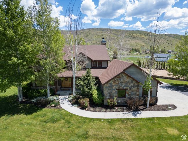 View of front facade featuring stone siding, a chimney, a front yard, and a mountain view | Image 79
