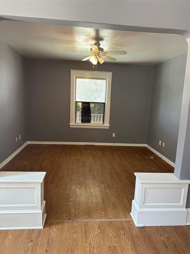 Empty room featuring arched walkways, baseboards, wood finished floors, and ceiling fan | Image 4