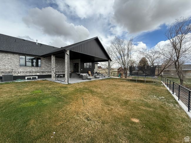 View of yard with a trampoline, cooling unit, fence, outdoor lounge area, and a patio | Image 27