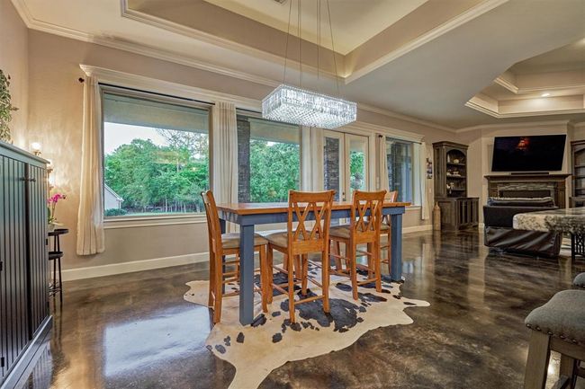 The dining area is elegantly accented by a sparkling crystal chandelier. Tray ceilings enhance the architectural detail and subtly define each space within the open floor plan. | Image 25