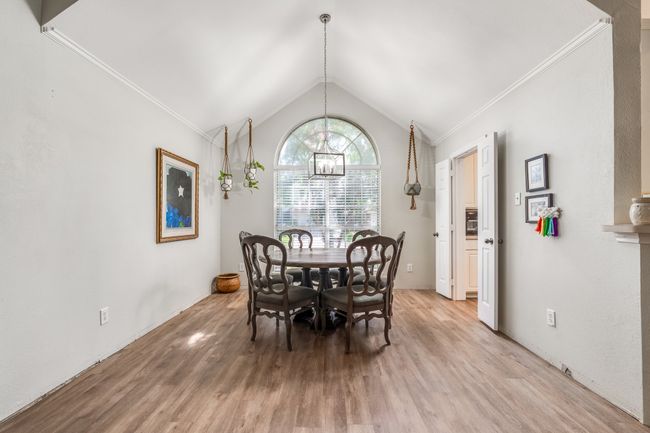 Dining room featuring light wood-style flooring, lofted ceiling, ornamental molding, and a chandelier | Image 16