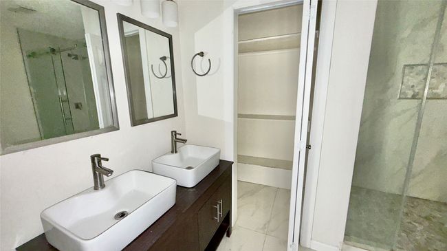 Full bathroom with a shower stall, marble look tile flooring, vanity, and a spacious closet | Image 24