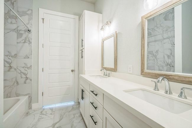 Full bathroom featuring marble finish flooring, double vanity, and washtub / shower combination | Image 5